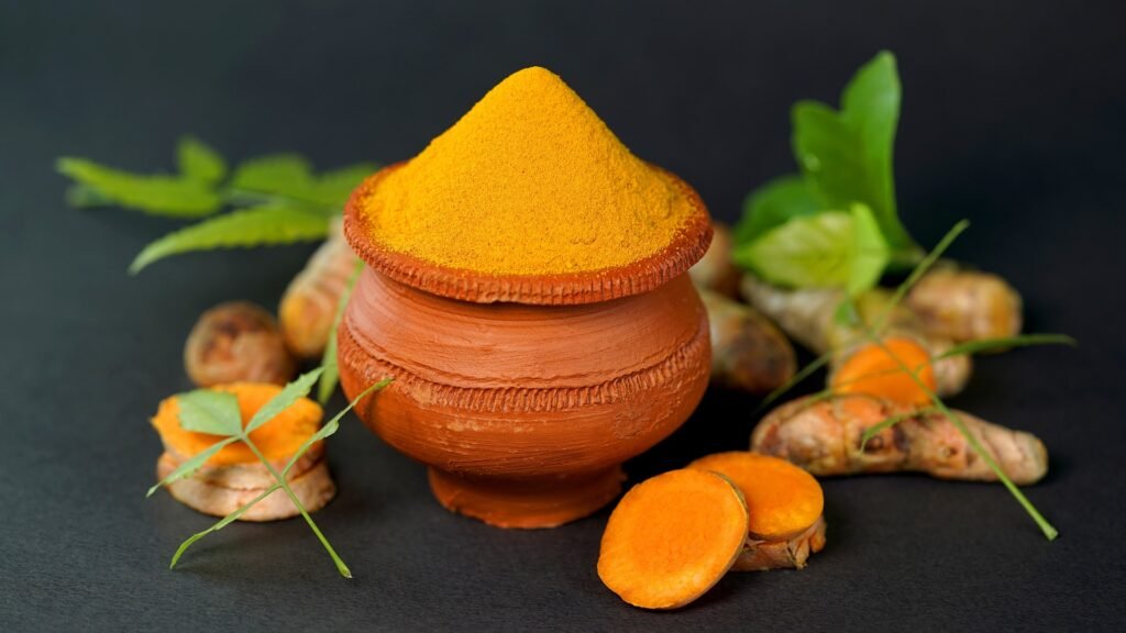 A small locally made clay cup of Turmeric powder and Turmeric sticks