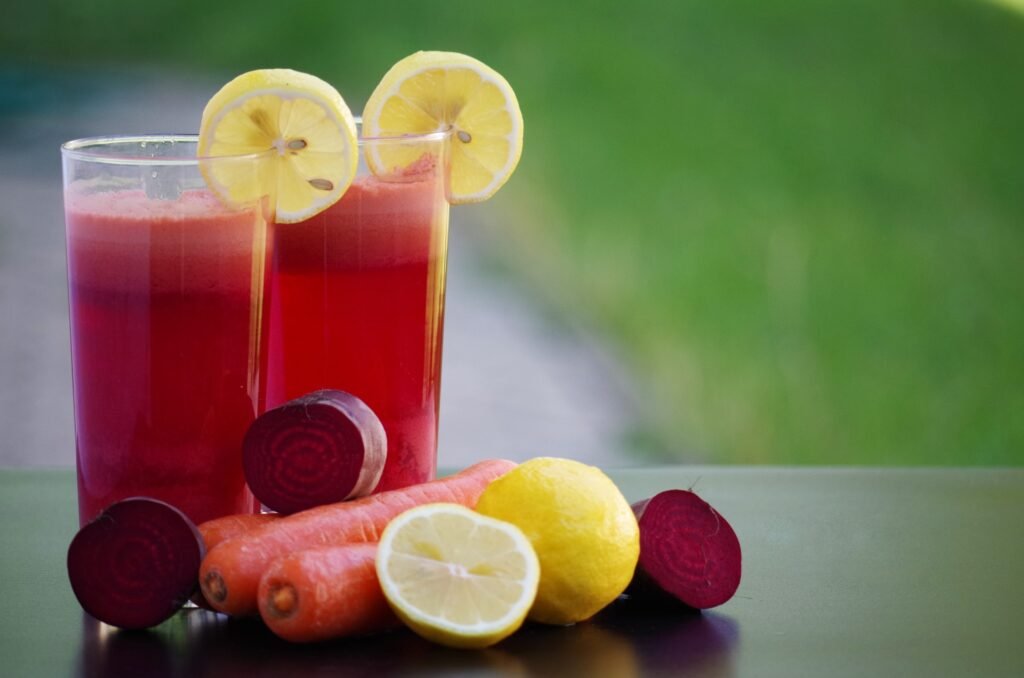 Cup of Juice made from beets, carrot, and lemon. The three fruits are displayed. 