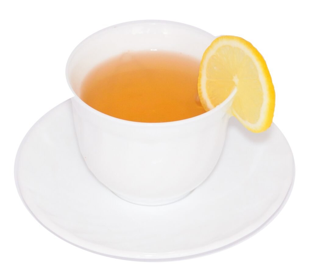 A white mug filled with green tea and a sliced lemon